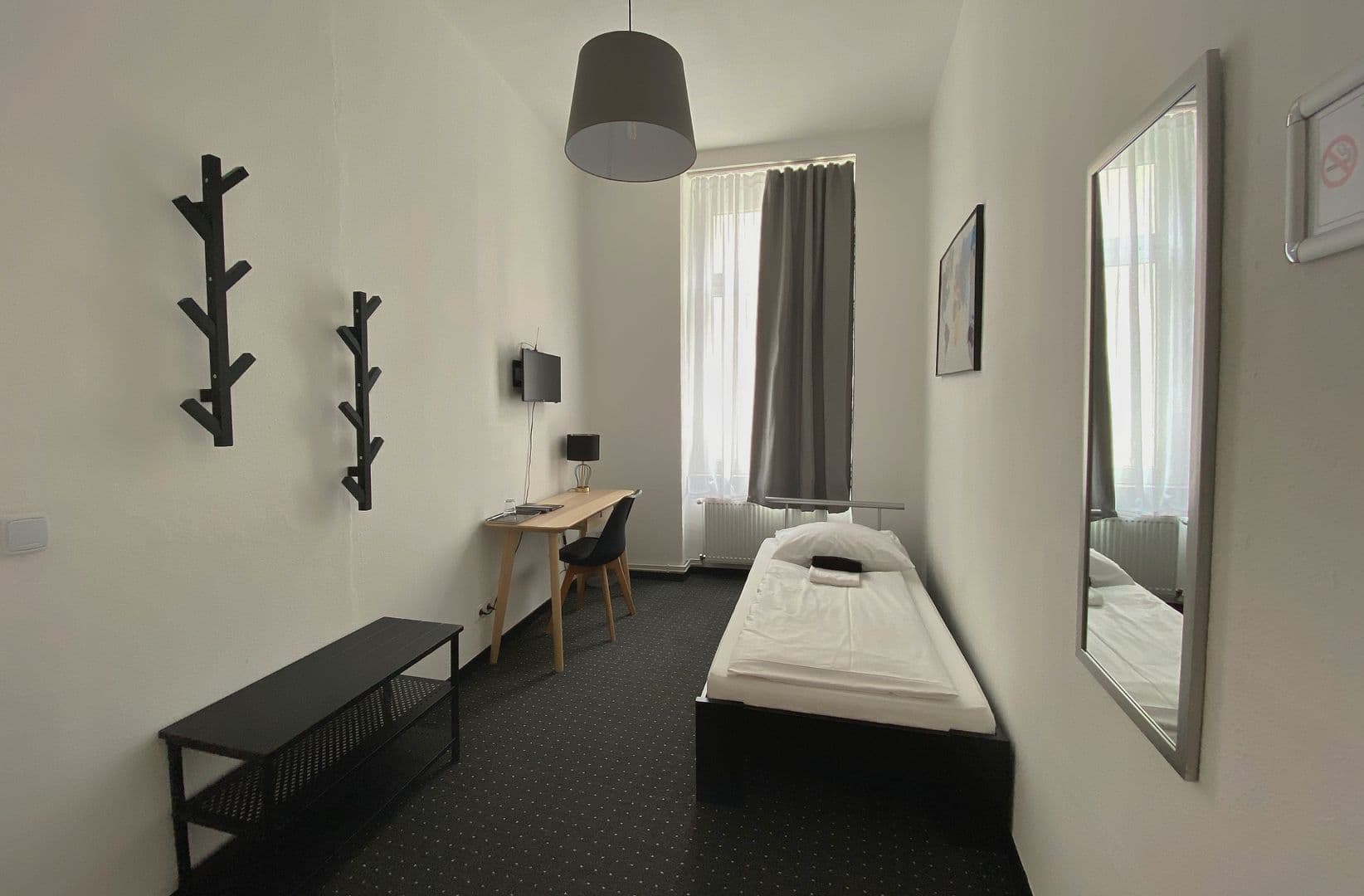 Blick in das Einzelzimmer mit Sitzbank, Garderobe und Schreibtisch