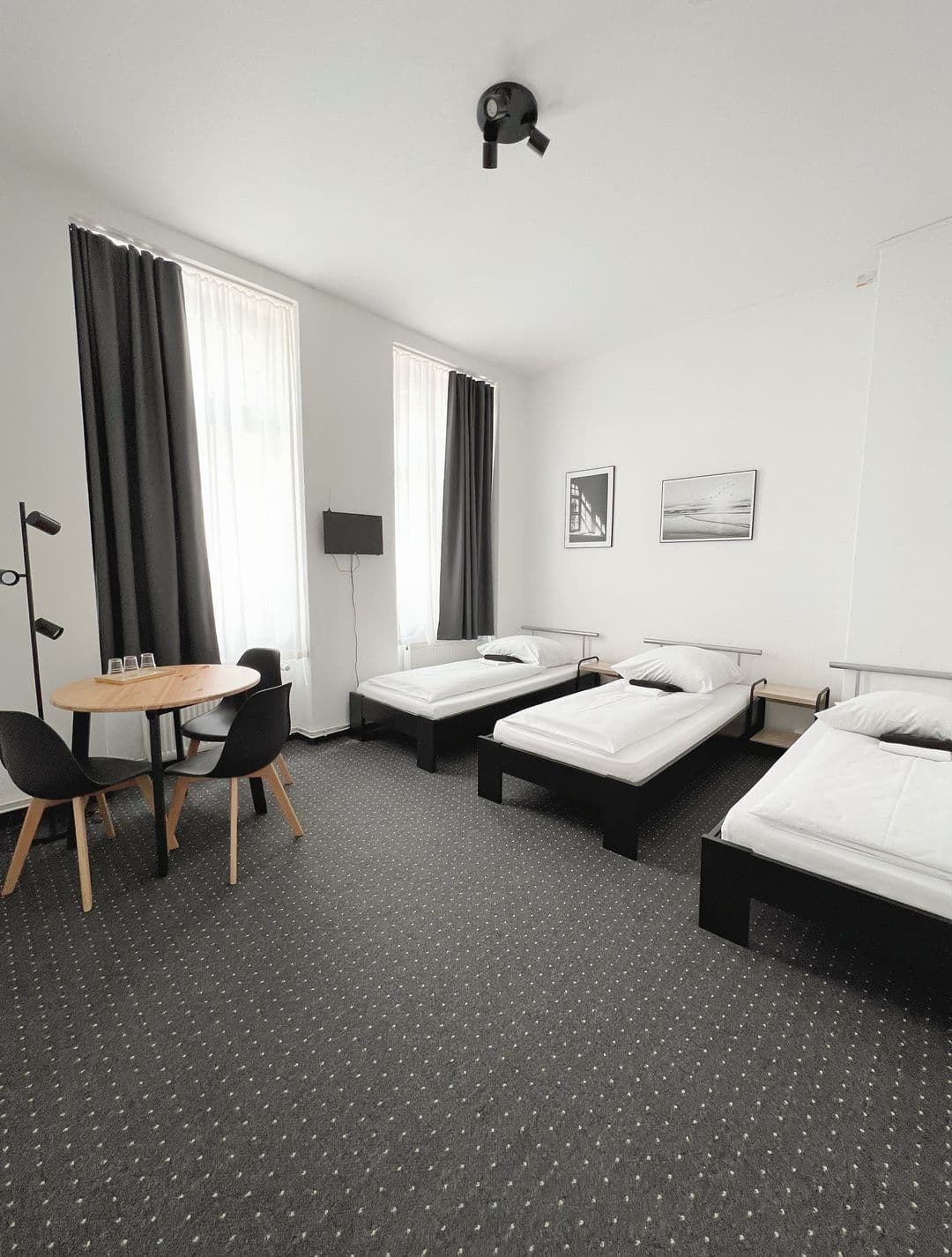 Dreibettzimmer Standard mit drei Betten und Tisch am Fenster